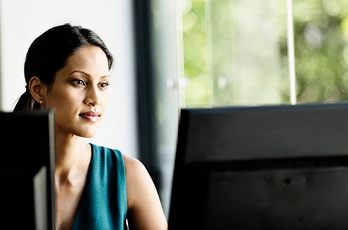 A professional reviewing some documents along with a computer, or something similar that can relate to a HR professional screening a candidate