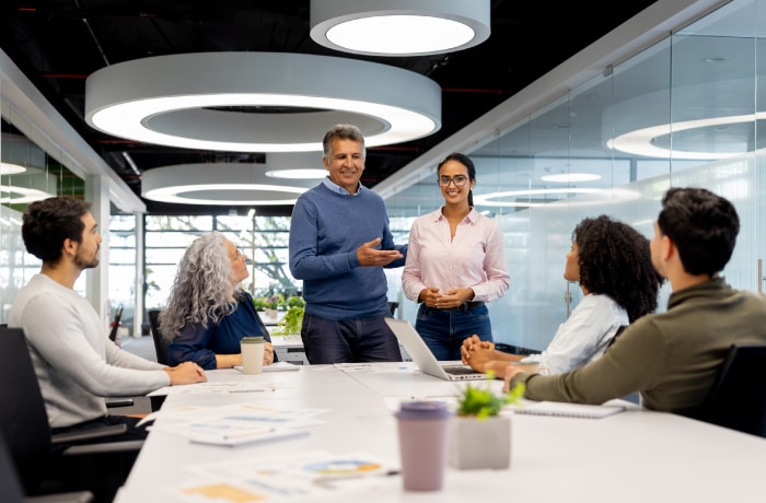 A professional hiring conversation involving a diverse team, with a subtle digital privacy or identity-verification layer. It should feel collaborative and human: candidates and hiring professionals reviewing information together.