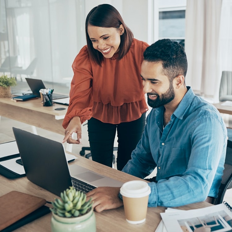 Two colleagues reviewing work together on a laptop