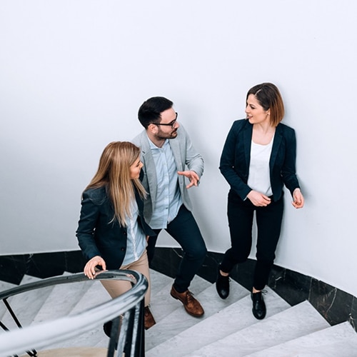 Three professionals discussing work while walking up the stairs