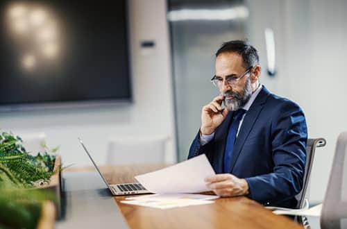 Mature adult businessman reviewing documents in office.