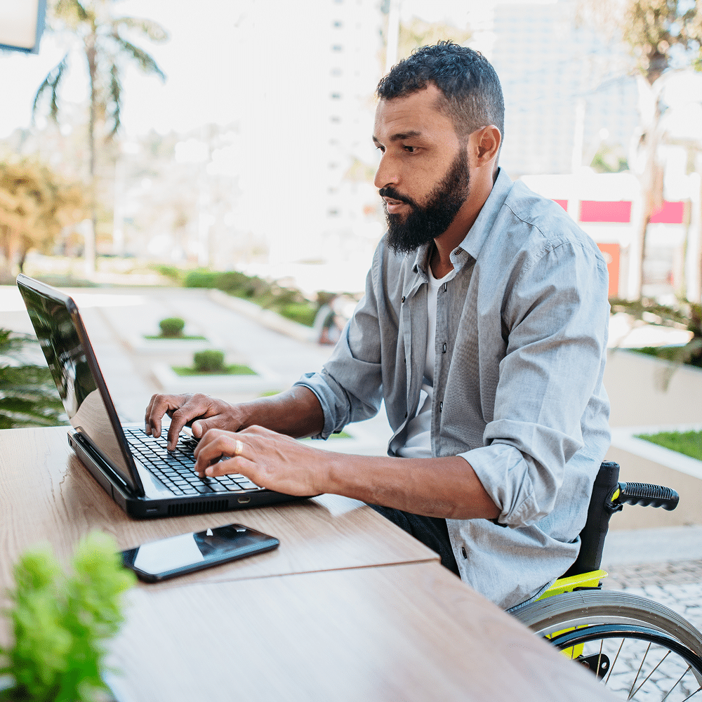 A male in a wheelchair typing on the computer.
