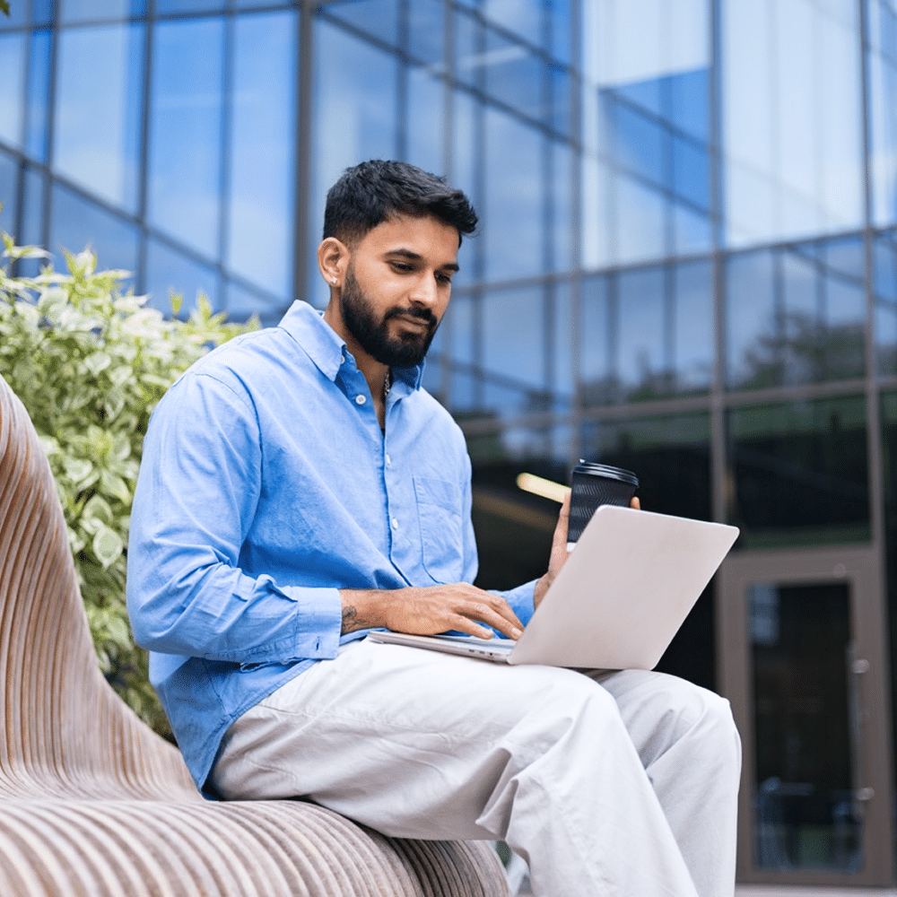 Person working on a laptop outside an office building.