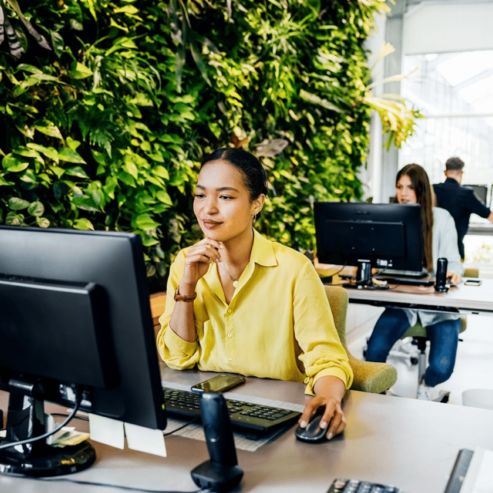 Employee working at computer with green leaves backdrop