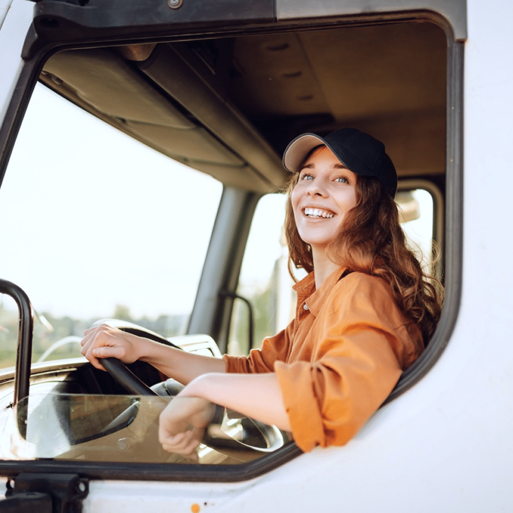Truck driver seated in a cab holding the steering wheel.