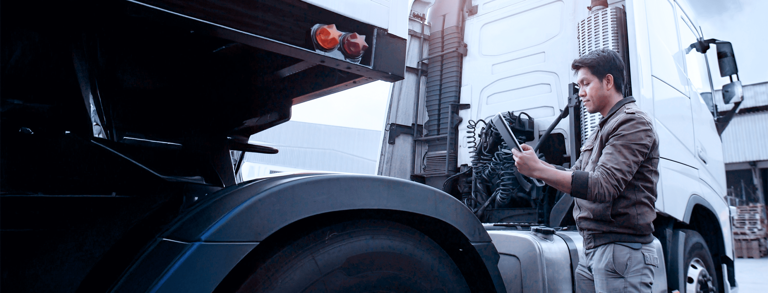 Worker inspecting a truck engine.