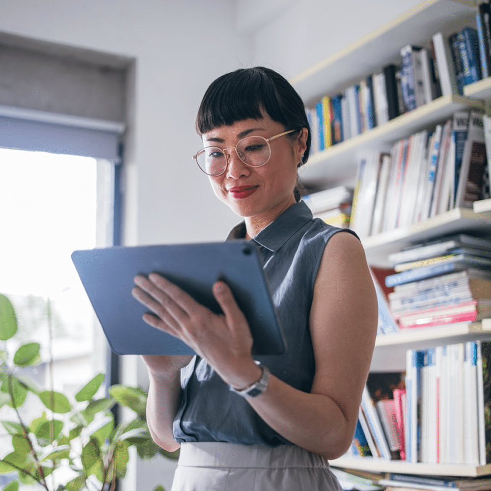Person holding a tablet in an office with bookshelves
