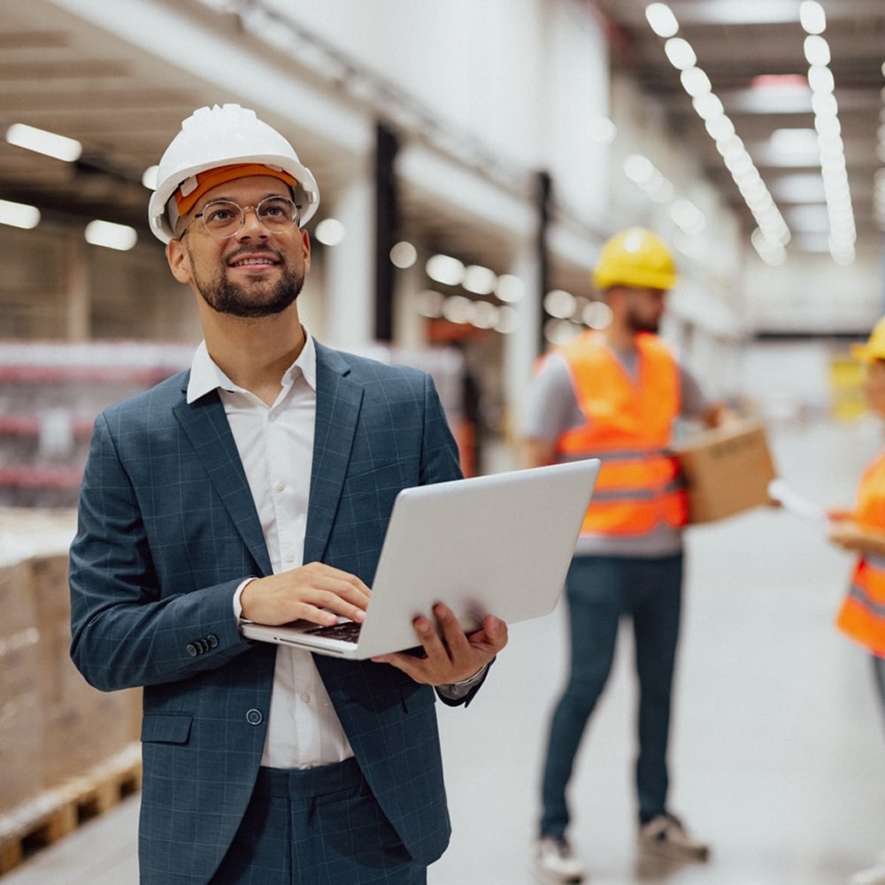 Manager using a laptop in a warehouse.