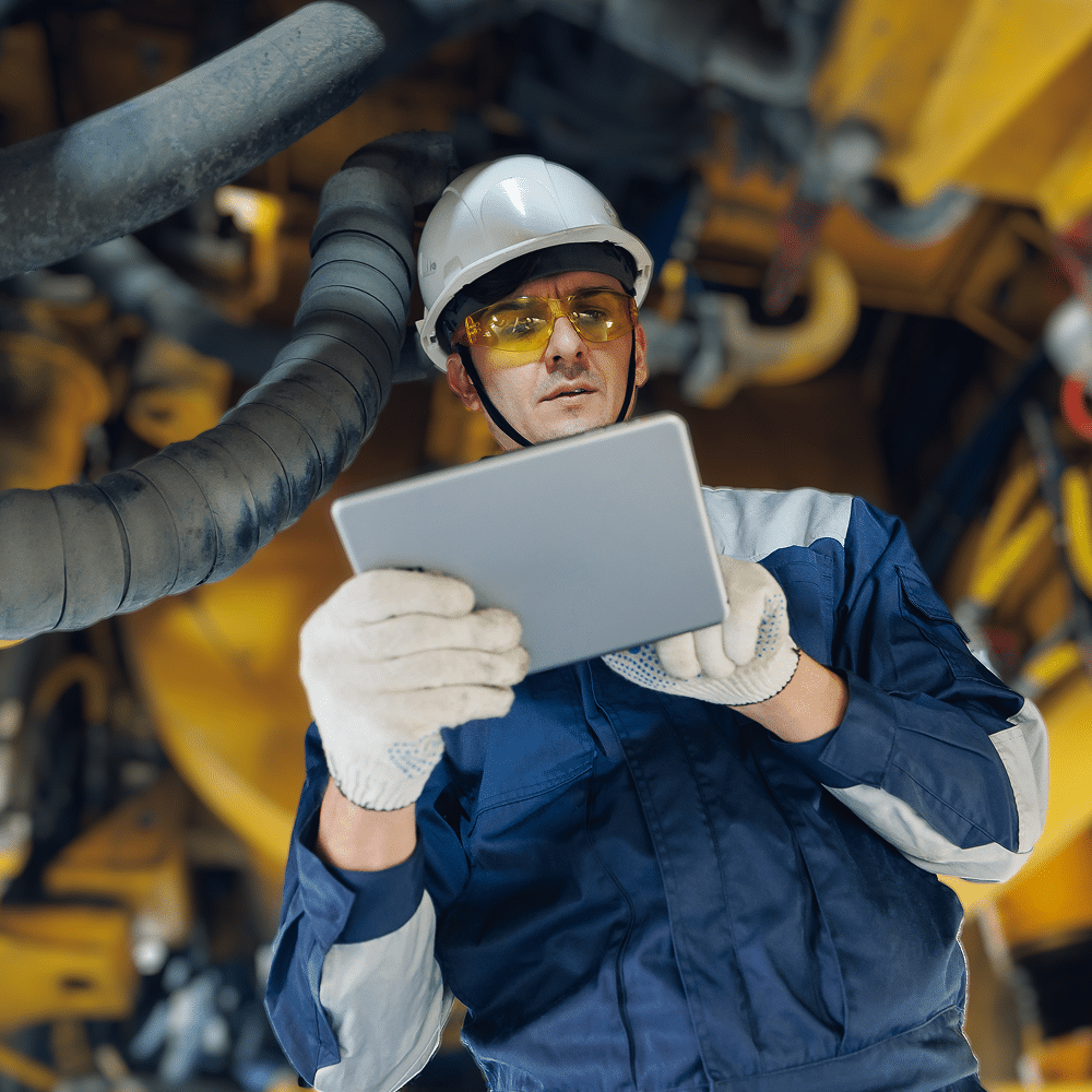 Worker using a tablet near industrial machinery.