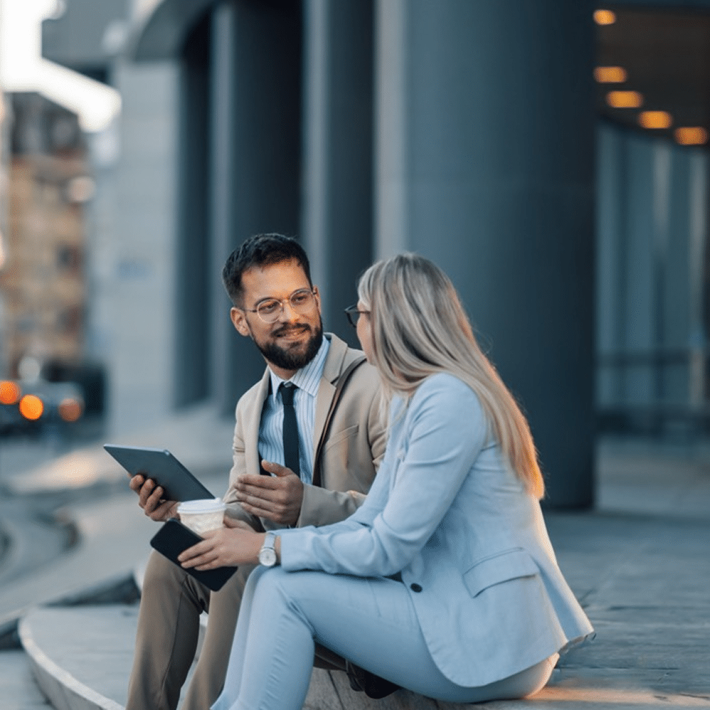 Two coworkers reviewing a tablet outside an office building.