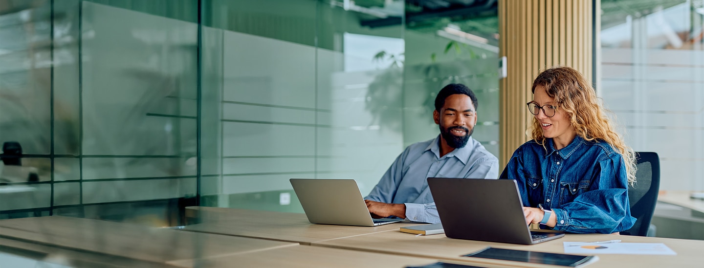 Two coworkers reviewing work on a laptop in an office.