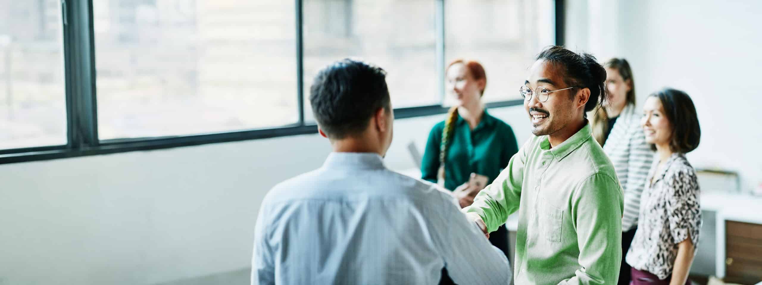 Diverse group of people shaking hands at a meeting.