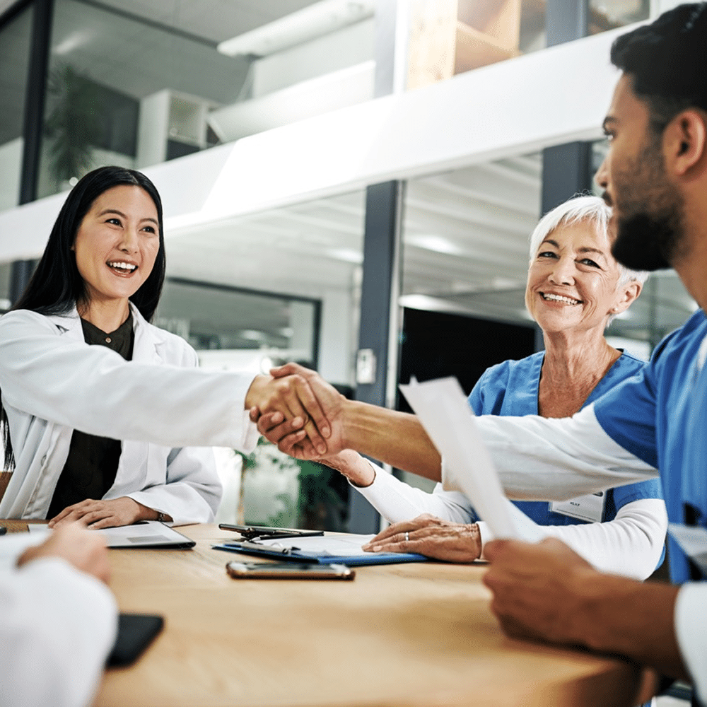 Medical staff shaking hands across a meeting table.