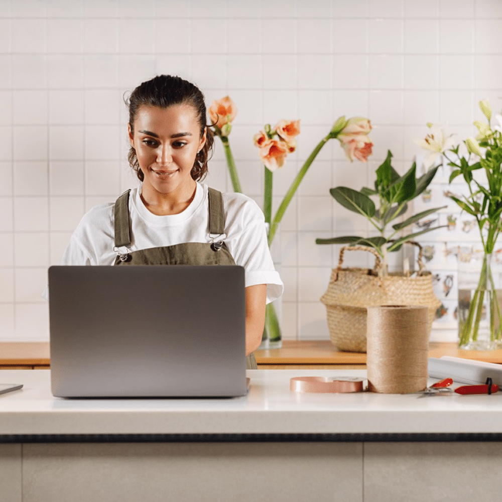 Person working on a laptop in a flower shop.