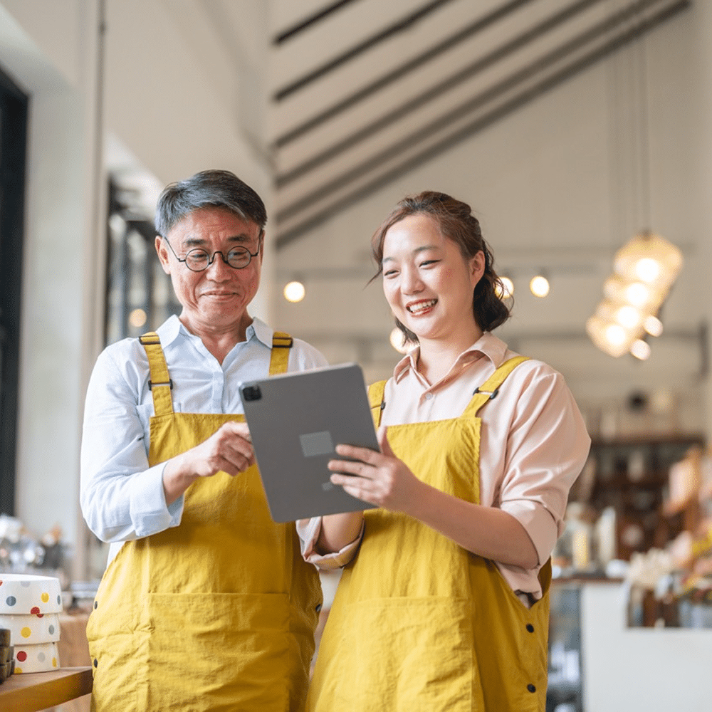 Two people reviewing a tablet in a small business shop.