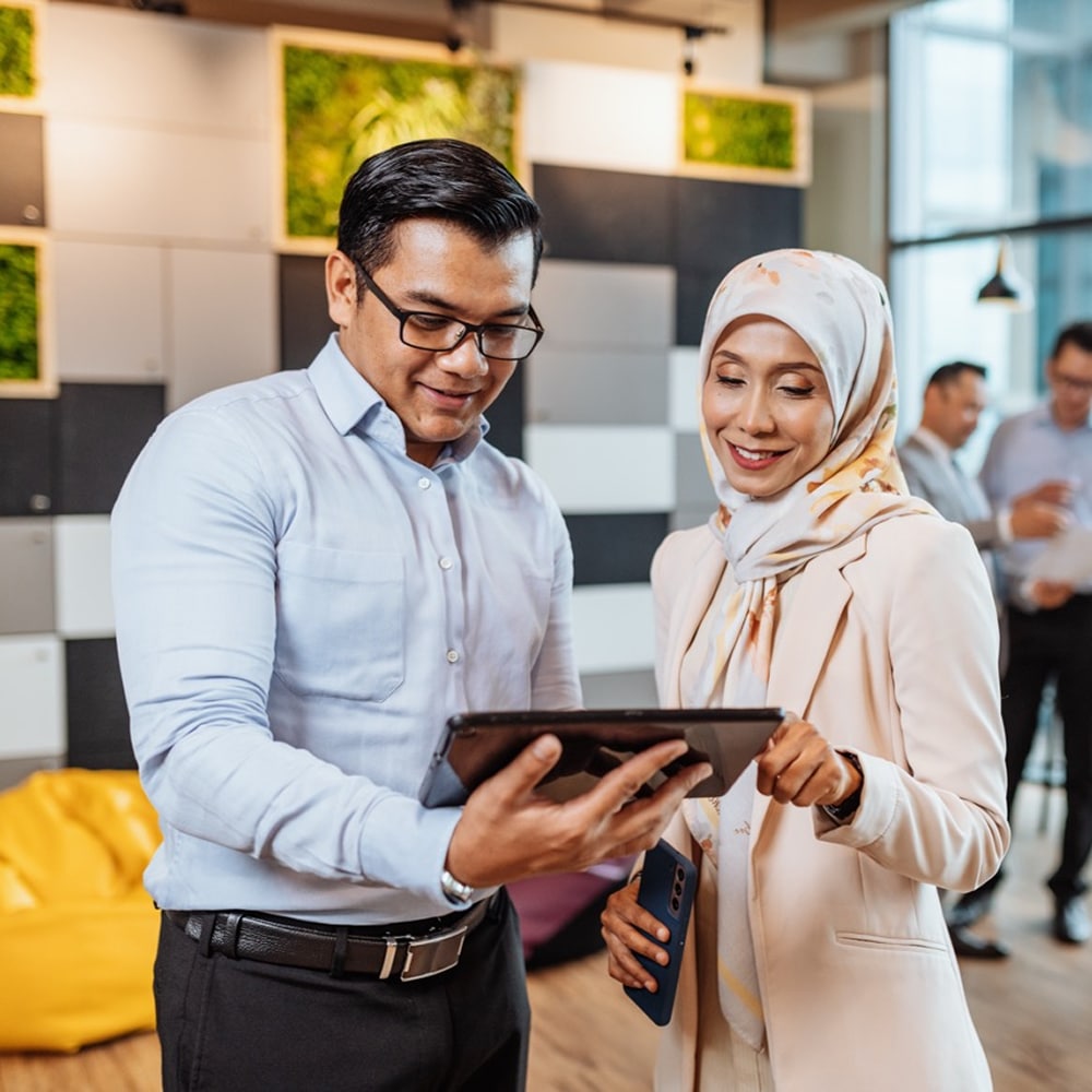 Diverse co-workers looking at a tablet in the office.