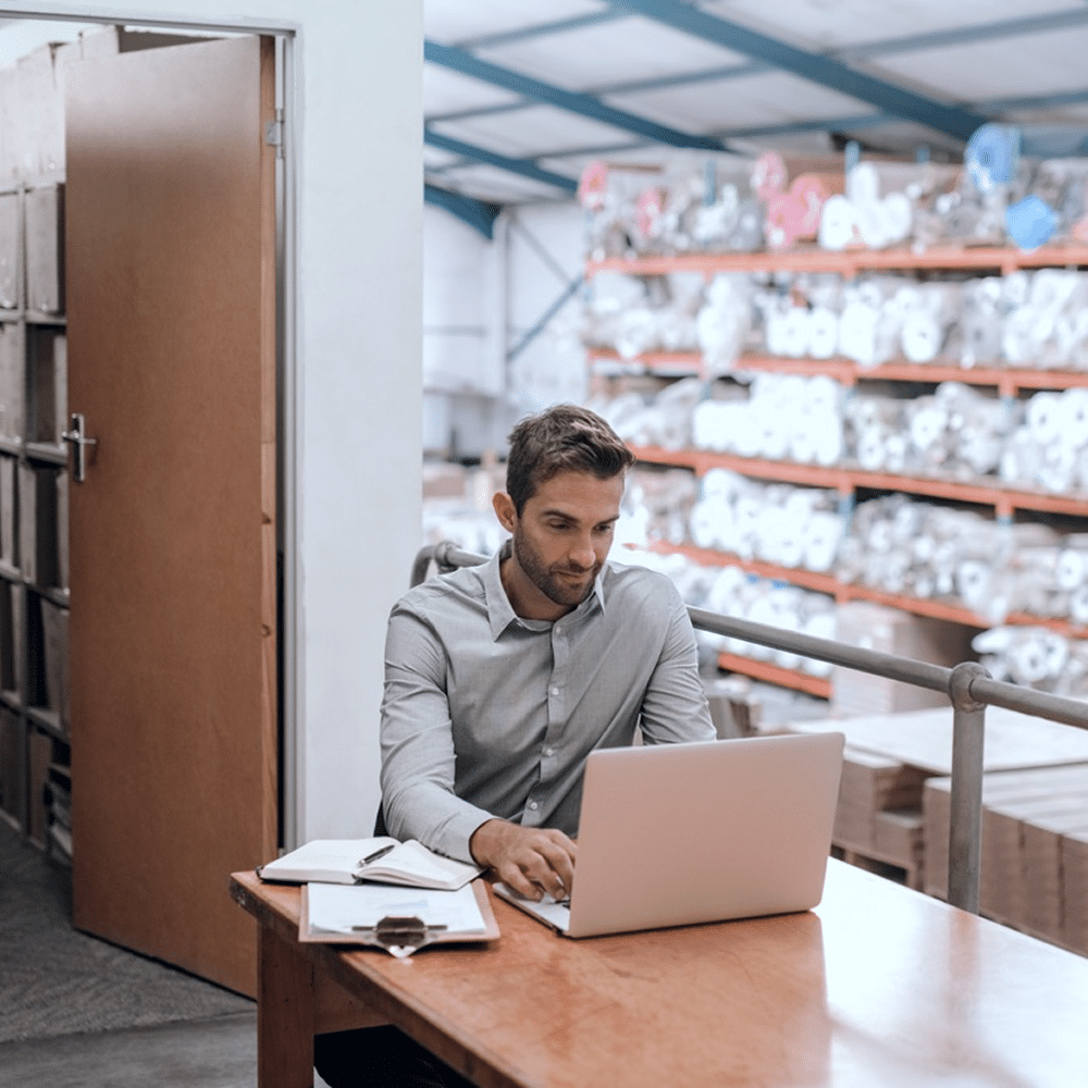Person working on a laptop in a warehouse.